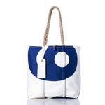 Sea Bags Vintage 95 Medium Tote—a white tote featuring a blue circular design, hand-spliced rope handles, and a white tag attached. Inspired by vintage sail tote traditions of Maine craftsmanship, this timeless piece is displayed against a white background. by Sea Bags