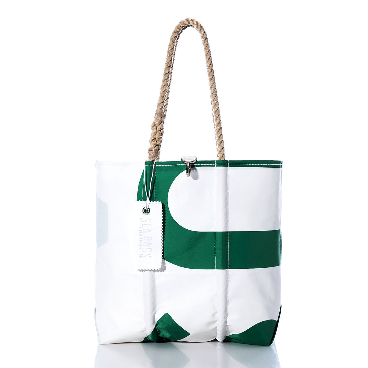 The Sea Bags Vintage USA Medium Tote features white and green sailcloth, rope handles, a metal clasp closure, and a rectangular white tag. Handmade in Maine and reminiscent of classic American totes, this bag stands upright on a reflective surface. by Sea Bags