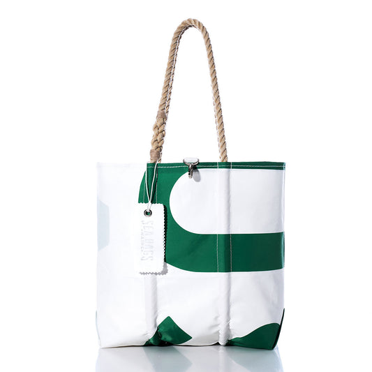 The Sea Bags Vintage USA Medium Tote features white and green sailcloth, rope handles, a metal clasp closure, and a rectangular white tag. Handmade in Maine and reminiscent of classic American totes, this bag stands upright on a reflective surface. by Sea Bags