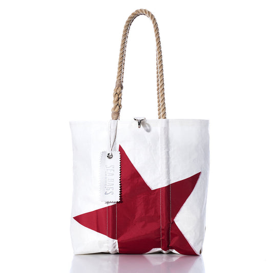 Sea Bags Vintage Red Star Medium Tote—crafted from white sailcloth, this handmade Maine tote features a striking red star motif, durable rope handles, and a white tag by the handle. Shown against a crisp white background. by Sea Bags