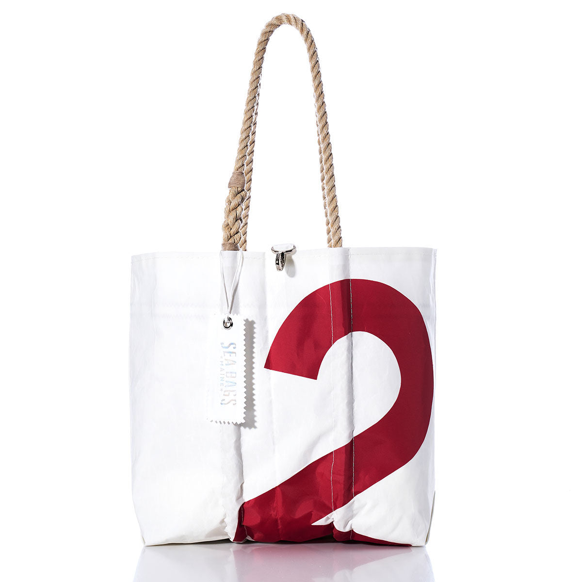 The Vintage Red 2 Medium Tote by Sea Bags is a white tote bag made from vintage sail cloth, featuring a bold red number 2 as its original sail insignia, hand-spliced rope handles, and a white SEABAGS tag attached to the handle. The product is photographed on a white background. by Sea Bags