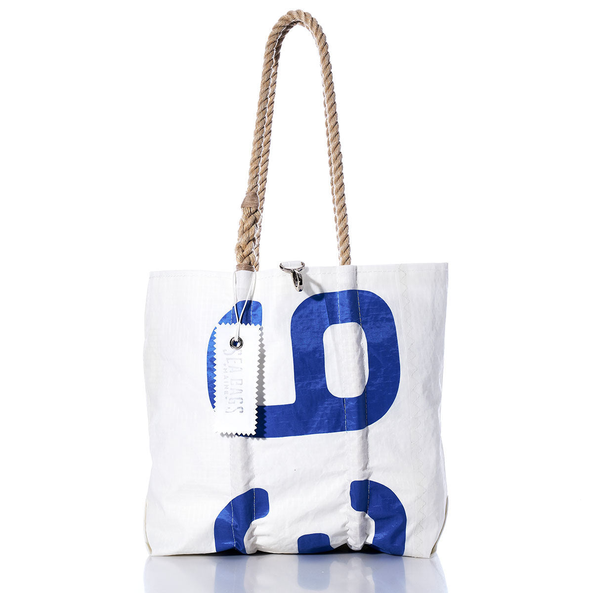 Sea Bags Vintage 93 Medium Tote, part of their Maine crafted bags collection, is shown on a white background. This white tote bag features blue print, hand-spliced rope handles, and a white tag attached. by Sea Bags