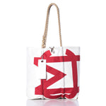 The Sea Bags Vintage Melges Medium Tote features a bold red geometric print on white, hand-spliced rope handles, and a white tag attached to one handle. Drawing inspiration from original sail insignia styles, this tote stands upright on a reflective white surface. by Sea Bags