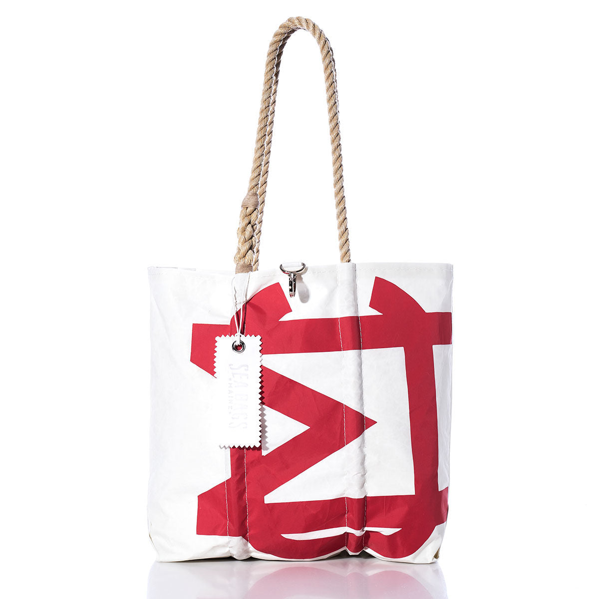 The Sea Bags Vintage Melges Medium Tote features a bold red geometric print on white, hand-spliced rope handles, and a white tag attached to one handle. Drawing inspiration from original sail insignia styles, this tote stands upright on a reflective white surface. by Sea Bags