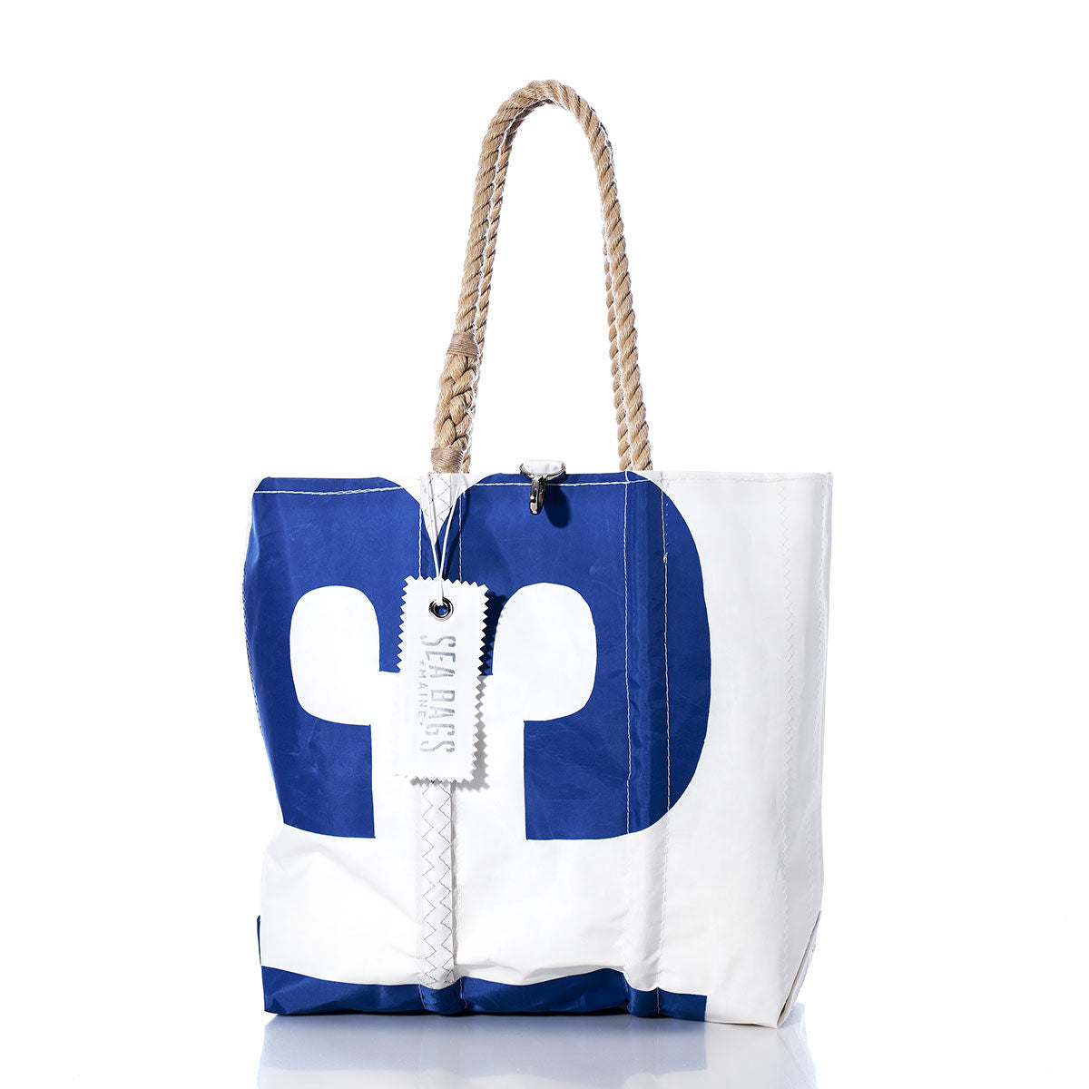 The Vintage 13 Medium Tote by Sea Bags features a white and blue design, hand-spliced rope handles, and a branded label, and is made in Maine; it is displayed on a white background. by Sea Bags