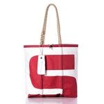The Sea Bags Vintage S8 Medium Tote features a red graphic design on white sailcloth, hand-spliced rope handles, and a white SEABAGS tag attached near the top. This tote showcases an original sail insignia for a distinctive nautical touch. by Sea Bags