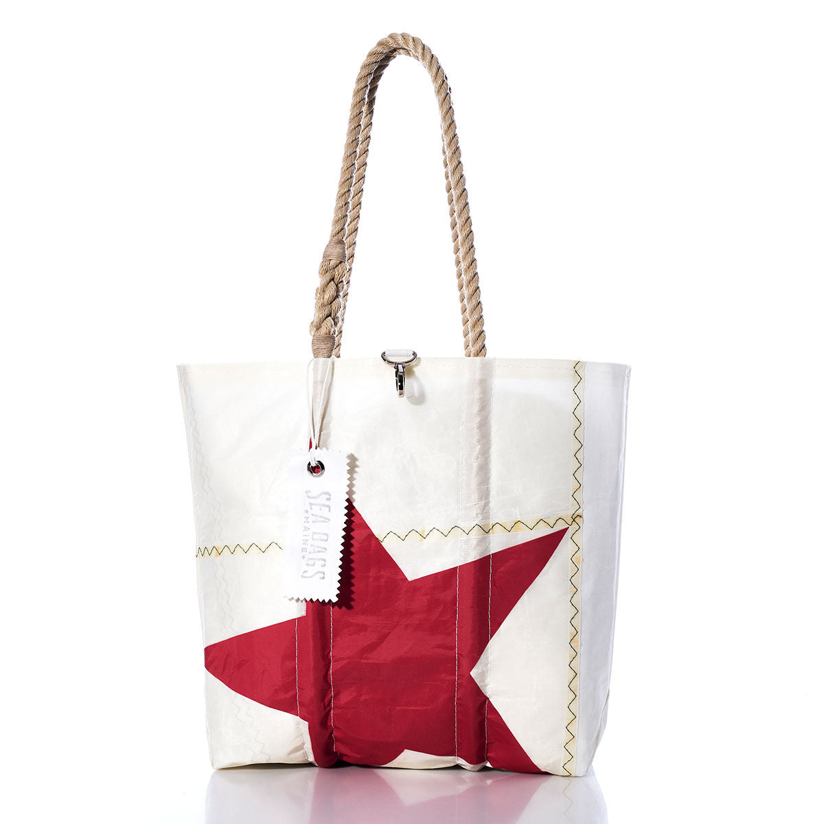 Introducing the Sea Bags Vintage Red Star Medium Tote—a white recycled sailcloth tote bag featuring sturdy rope handles, a bold red star design, and a signature white Sea Bags tag. Expertly handmade in Maine, this tote combines distinctive style with durable craftsmanship. by Sea Bags