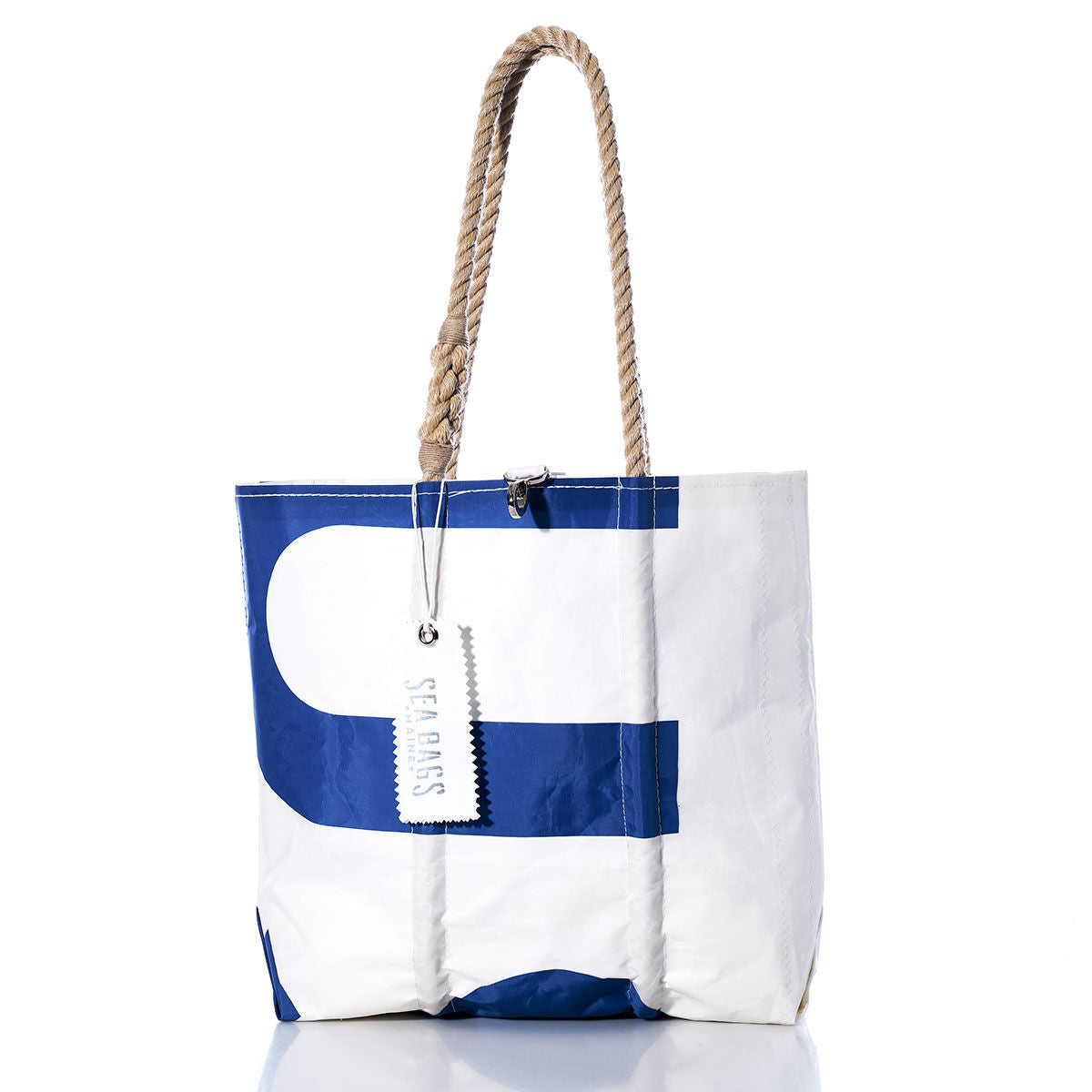 The Sea Bags Vintage USA Medium Tote is a white and blue tote bag featuring hand-spliced rope handles, a zipper closure, and a white SEABAGS tag attached to one handle. This Maine handcrafted bag is shown on a white background. by Sea Bags