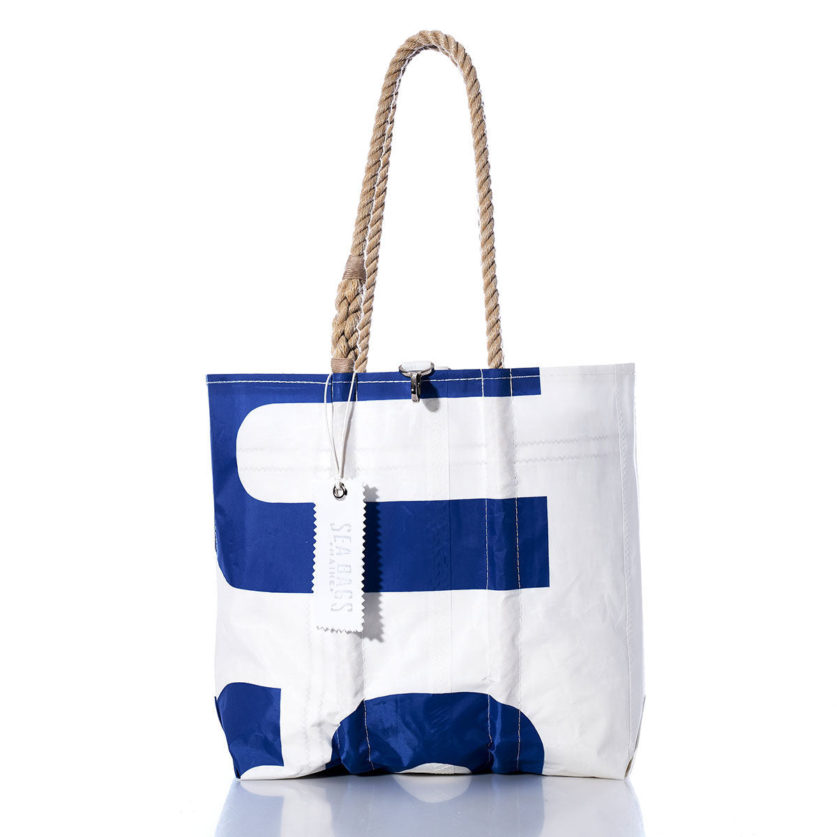 A white Vintage USA Medium Tote by Sea Bags, featuring bold blue letters, rope handles, and crafted from durable sailcloth with a tag labeled SHIPS, is displayed against a white background. by Sea Bags