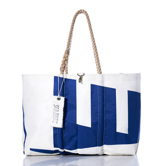 The Vintage Etchells Large Tote by Sea Bags features a distinctive large blue geometric design on white sailcloth, complemented by sturdy rope handles and a SEA BAGS logo tag. Handcrafted in Maine from authentic recycled sails, this spacious tote offers durability and nautical style for everyday adventures—all set against a crisp white background. by Sea Bags