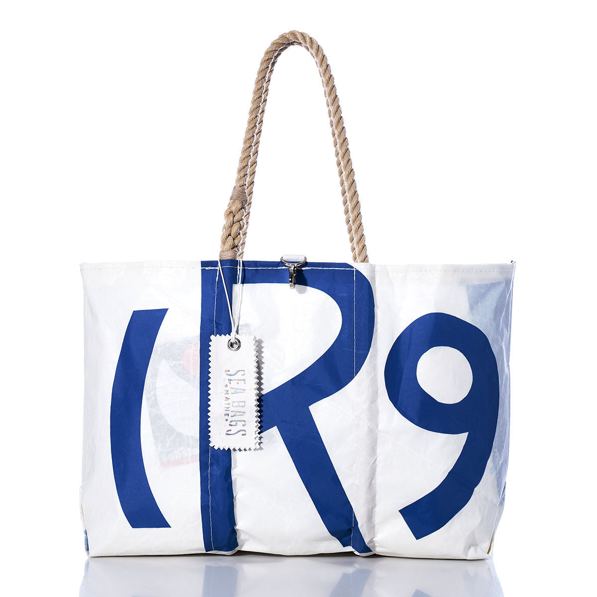 Vintage Rhodes 19 Large Tote by Sea Bags—a handcrafted Maine tote made from durable sailcloth, featuring a white body with a blue R9 print, rope handles, and a white Sea Bags tag; photographed against a white background. by Sea Bags