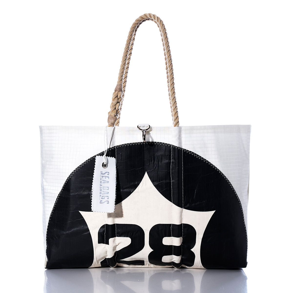 The Vintage 28 Large Tote by Sea Bags is a handmade Maine bag crafted from white and black sailcloth, featuring the number 28, sturdy rope handles, and a signature Sea Bags tag. Photographed against a white background, this tote showcases classic style paired with durable craftsmanship. by Sea Bags