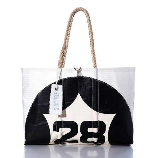 The Vintage 28 Large Tote by Sea Bags is a handmade Maine bag crafted from white and black sailcloth, featuring the number 28, sturdy rope handles, and a signature Sea Bags tag. Photographed against a white background, this tote showcases classic style paired with durable craftsmanship. by Sea Bags