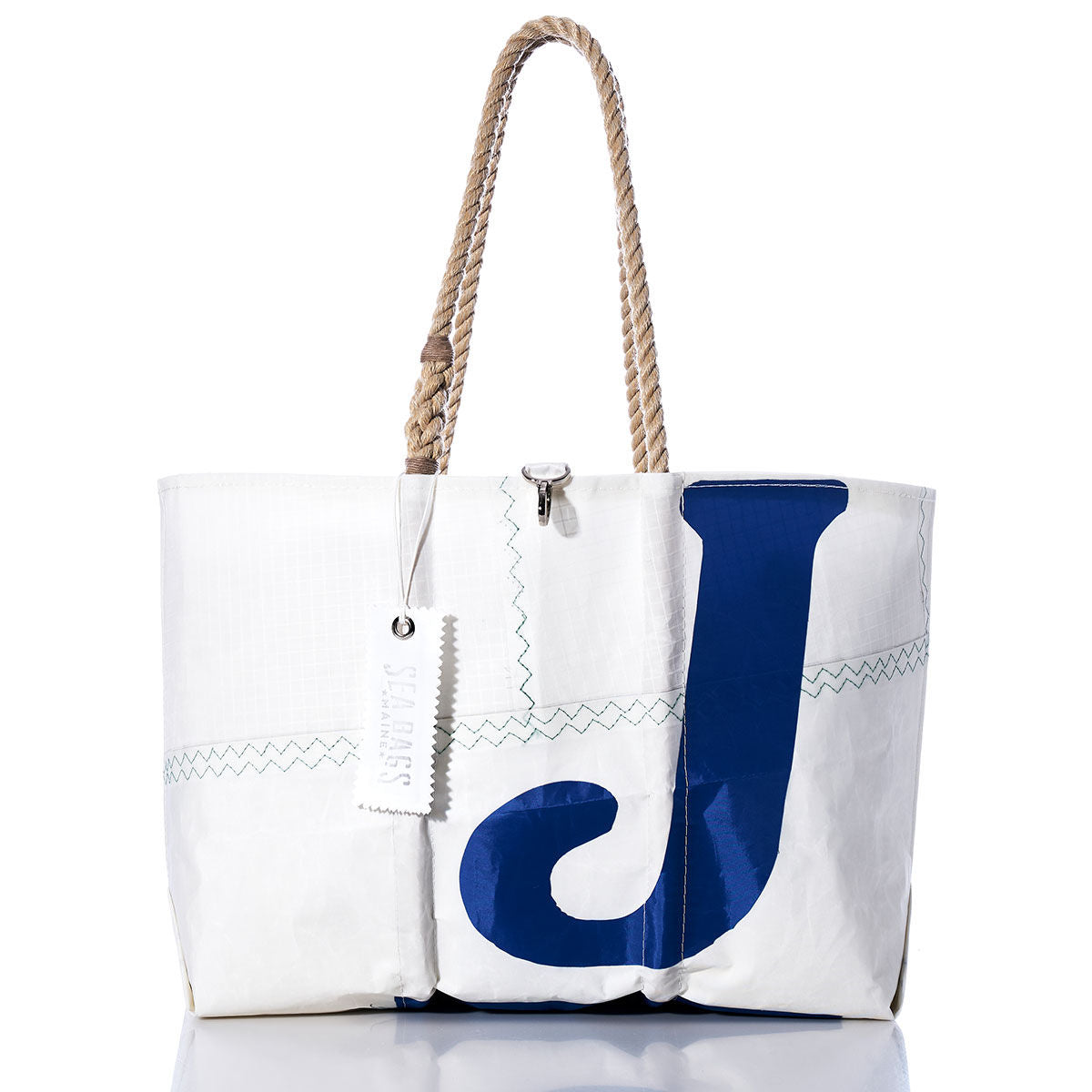 White sailcloth tote bag with rope handles, featuring a bold navy blue letter J on the front, visible stitching, and a white tag attached to one handle. The Sea Bags Vintage J70 Large Tote is part of our collection of handcrafted totes, offering both durability and timeless style. by Sea Bags