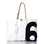 The Sea Bags Vintage Black 6 Large Tote is a white tote bag crafted with hand-spliced rope handles, featuring a bold black number six graphic on the right side and finished with a white tag near the handle—genuine vintage sail style inspired by authentic sail insignia. by Sea Bags