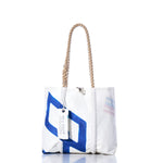 Sea Bags Vintage 470 Handbag—a white tote adorned with a blue geometric sail insignia pattern, featuring sturdy hemp rope handles and finished with a signature Sea Bags tag—displayed on a white background. by Sea Bags