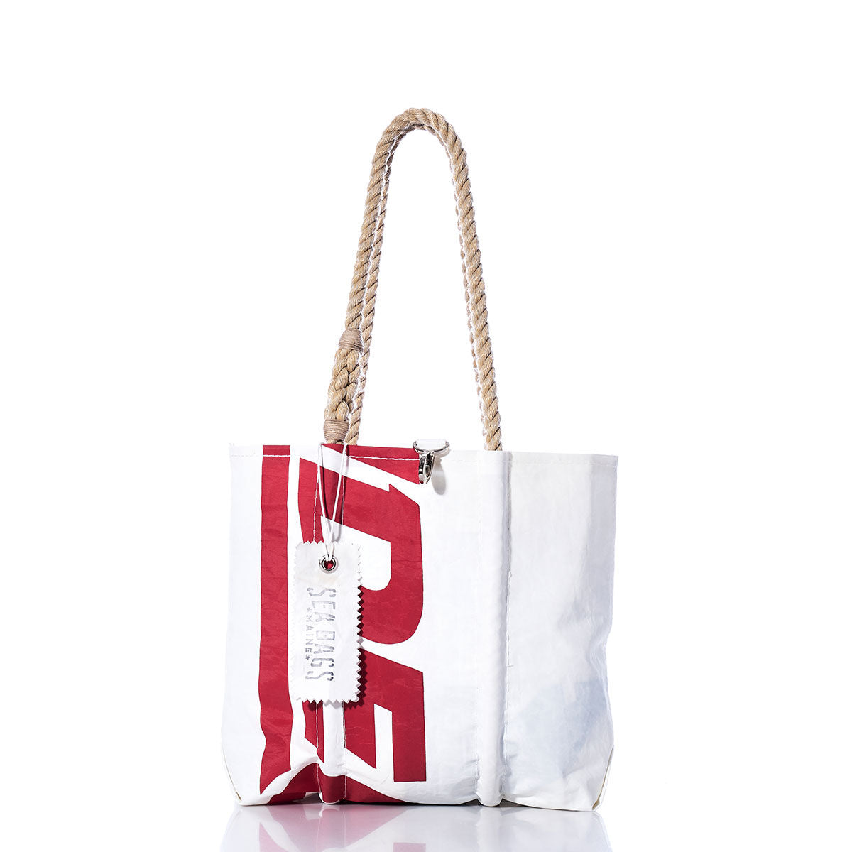 Sea Bags Vintage Ideal 18 Handbag: white tote bag with red lettering inspired by vintage sail insignias, beige hemp rope handles, and a white tag labeled SUSSES, photographed against a plain white background. by Sea Bags