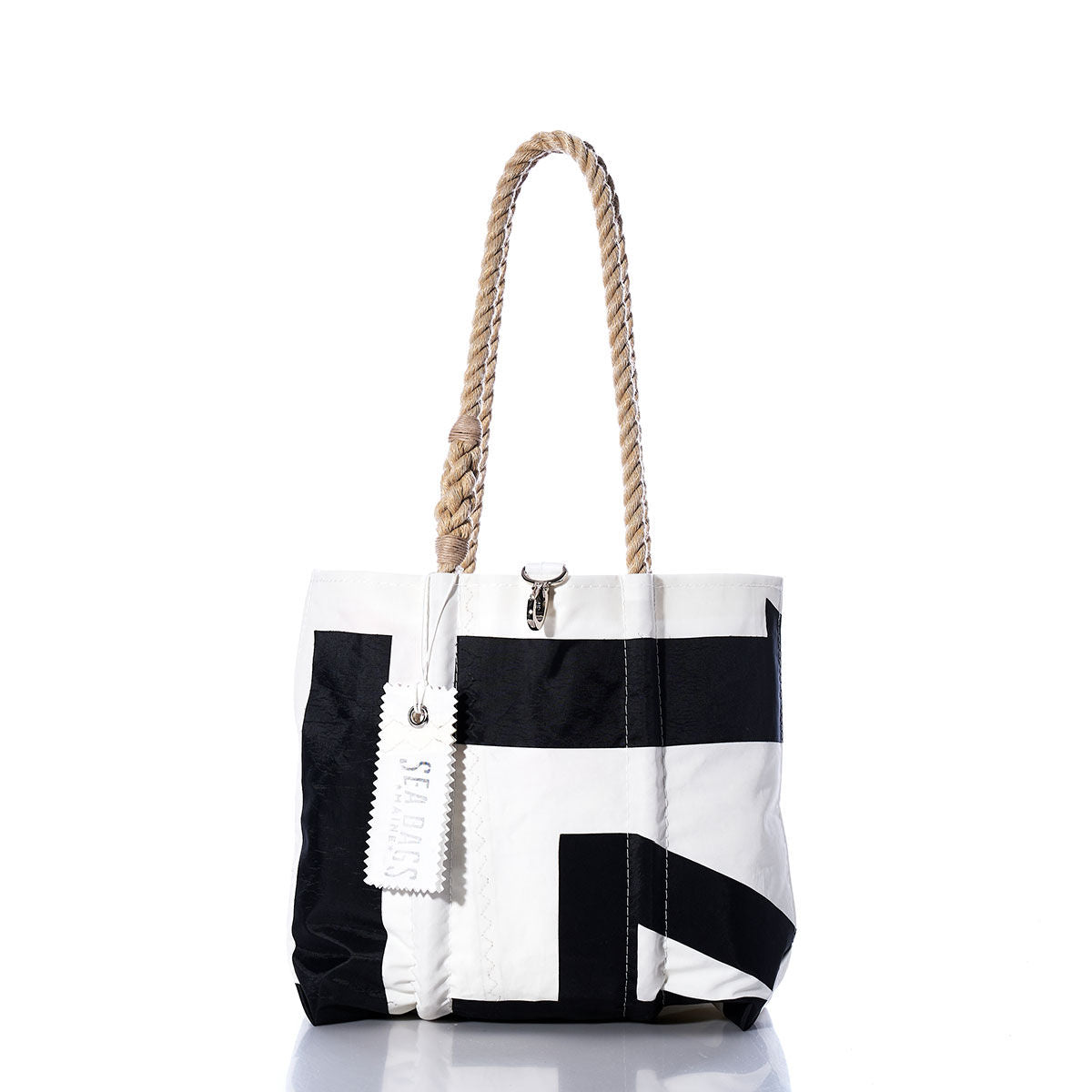 Sea Bags Vintage International 14 Handbag – a black and white tote with durable hemp rope handles and an attached white tag. Displayed on a white background with a slight reflection, this stylish accessory draws inspiration from classic International 14 handbag designs and is adorned with subtle sail insignias for an elegant nautical flair. by Sea Bags