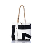 Sea Bags Vintage International 14 Handbag – a black and white tote with durable hemp rope handles and an attached white tag. Displayed on a white background with a slight reflection, this stylish accessory draws inspiration from classic International 14 handbag designs and is adorned with subtle sail insignias for an elegant nautical flair. by Sea Bags