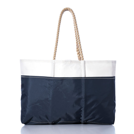 A Sea Bags Vintage Lightning Ogunquit Beach Tote, featuring navy blue and white hues with rope handles and crafted from recycled sail cloth, is photographed against a white background. by Sea Bags