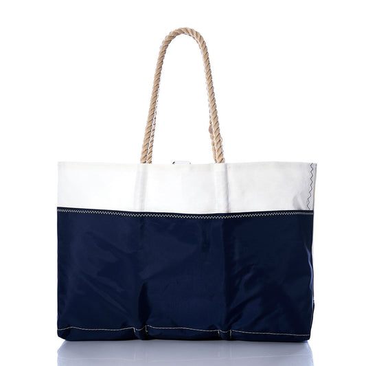 The Sea Bags Vintage Ensign Ogunquit Beach Tote is a two-toned beach tote bag made from recycled sail cloth, showcasing a navy blue lower section and white upper section with two rope handles, photographed against a white background. by Sea Bags