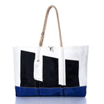The Sea Bags Vintage Etchells Ogunquit Beach Tote is a large white beach bag crafted from recycled sail cloth, featuring bold black geometric shapes, a blue bottom edge, sturdy rope handles, and a white tag attached—all inspired by vintage Etchells sails. by Sea Bags