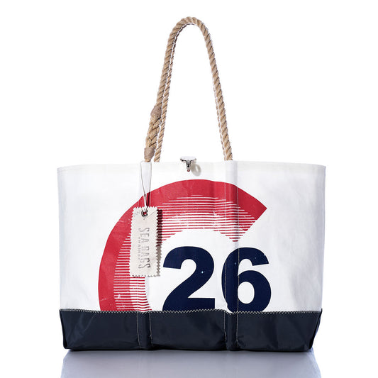 The Sea Bags Vintage Colgate 26 Ogunquit Beach Tote is a large white and black tote with rope handles, crafted from recycled sail cloth and adorned with a bold red and blue vintage Colgate 26 design. It features a SEA BAGS tag attached to one handle. by Sea Bags