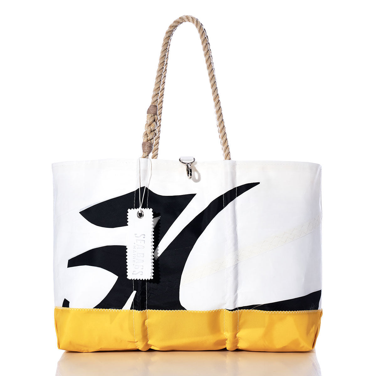 The Sea Bags Vintage Hobie Ogunquit Beach Tote is a large beach tote bag with rope handles, expertly crafted from recycled sail cloth in bold white, black, and yellow panels. Showcasing an eye-catching abstract design inspired by vintage Hobie sails and finished with a white tag near the handle, this spacious tote blends standout style with eco-friendly sustainability. by Sea Bags