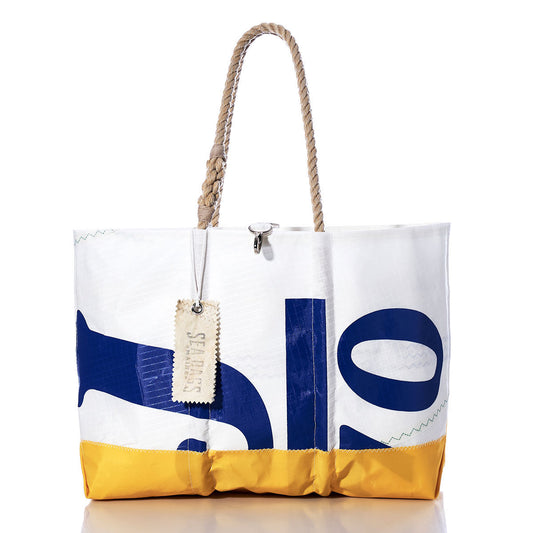 The Vintage J70 Ogunquit Beach Tote by Sea Bags is crafted from recycled sail cloth, featuring a yellow bottom, blue printed letters, sturdy rope handles, and a stitched SEABAGS tag attached to one handle. by Sea Bags