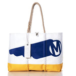 Sea Bags’ Vintage Mercury Ogunquit Beach Tote is a white recycled sail cloth bag with a yellow base, blue graphic featuring a large M in a circle inspired by vintage Mercury branding, durable rope handles, and a silver zipper pull engraved with “SMITHS.”. by Sea Bags