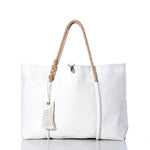 The Sea Bags Vintage Orange Graphic Wharf Tote is a white canvas bag handcrafted in Portland, Maine from recycled sail materials. Featuring rope handles, a front pocket, and a SEA BAGS tag, this tote showcases vintage orange graphic accents inspired by the iconic Wharf Tote design. The product is pictured against a white background. by Sea Bags