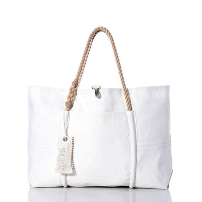 The Sea Bags Vintage Orange Graphic Wharf Tote is a white canvas bag handcrafted in Portland, Maine from recycled sail materials. Featuring rope handles, a front pocket, and a SEA BAGS tag, this tote showcases vintage orange graphic accents inspired by the iconic Wharf Tote design. The product is pictured against a white background. by Sea Bags