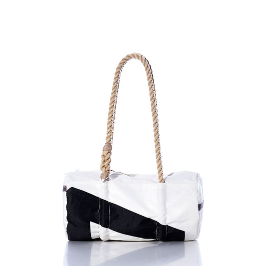 The Sea Bags Vintage Black 7 Baguette Bag is a white and black cylindrical bag featuring a thick, hand-spliced hemp rope handle. Displayed on a reflective surface against a white background, its classic vintage baguette shape is complemented by subtle sail insignias for a nautical touch. by Sea Bags