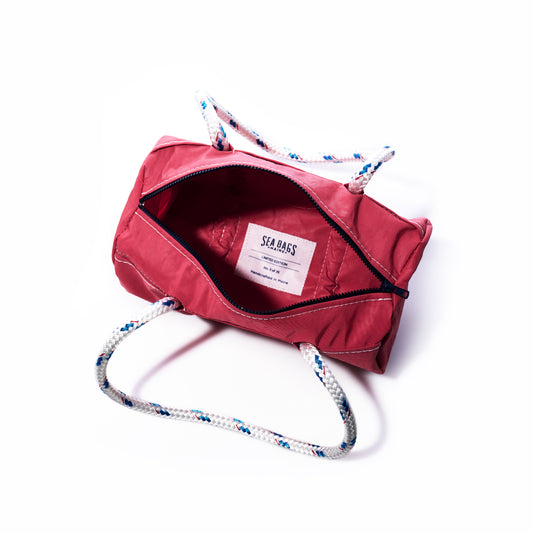 Pink duffel bag with rope handles on a white background