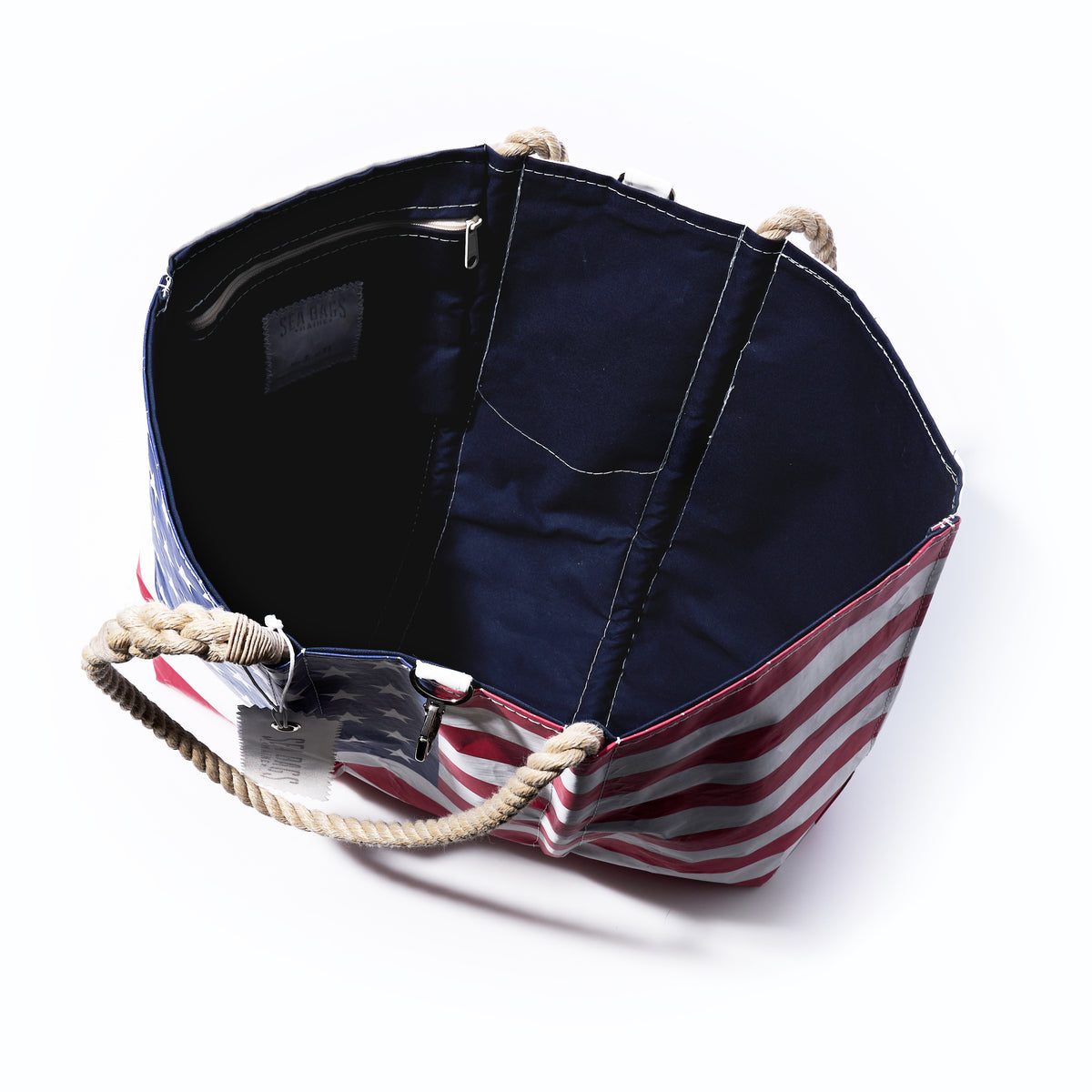 Handcrafted in the USA from recycled sail cloth, the Sea Bags Vintage Limited Edition American Flag Large Tote features sturdy rope handles, a dark fabric interior with a visible pocket, and is beautifully photographed from above. Combining patriotic style with sustainable craftsmanship, it’s an iconic accessory for any occasion.