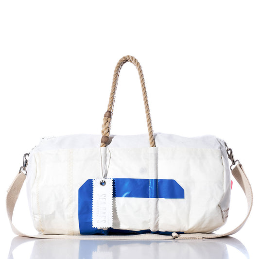 The Vintage US Duffel by Sea Bags features a white exterior with blue accents, a beige shoulder strap, and durable hemp rope handles. Crafted from recycled sail cloth, it includes a signature white Sea Bags tag and is shown on a reflective surface against a white background. by Sea Bags