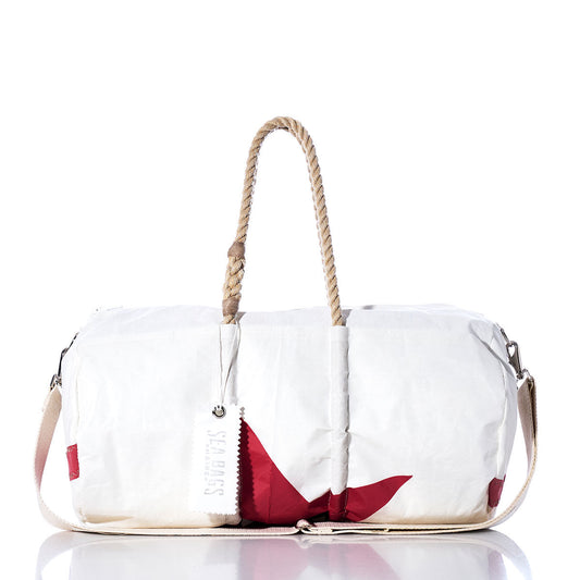 The Vintage Red Star Duffel by Sea Bags is a white duffel bag with red accents, featuring hemp rope handles, a beige shoulder strap, and a white tag labeled Sea Bags. Crafted from recycled sail cloth, it is shown against a white background. by Sea Bags