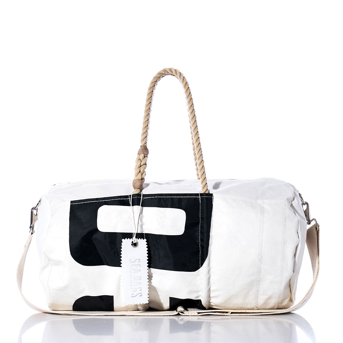 The Sea Bags Vintage 039 Duffel is a white vintage-style duffel bag featuring a black graphic print, hemp rope handles, a detachable shoulder strap, and a tag labeled Sea Bags. Crafted from recycled sail cloth, the bag is displayed against a white background. by Sea Bags