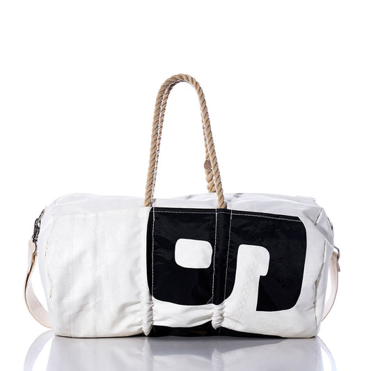 The Sea Bags Vintage 039 Duffel, crafted from recycled sail cloth with a black geometric design, features sturdy hemp rope handles and a beige shoulder strap. It is displayed on a reflective surface against a white background. by Sea Bags