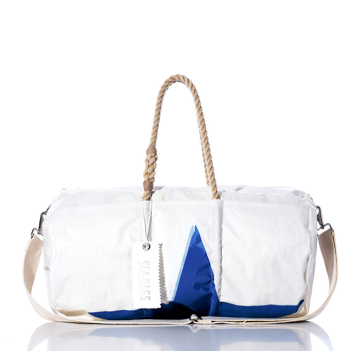 Sea Bags Vintage Blue Star Duffel, expertly crafted from recycled sail cloth in crisp white and blue, features durable hemp rope handles, a beige shoulder strap, and a signature white tag—elegantly showcased on a reflective surface. by Sea Bags