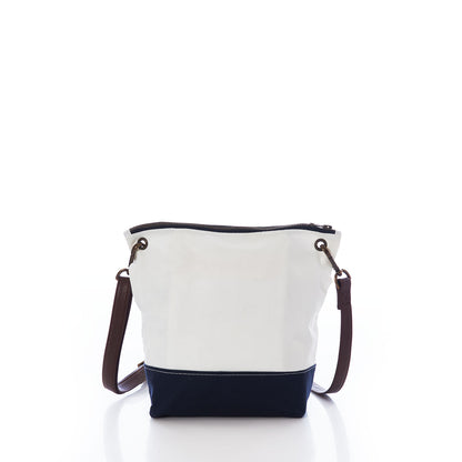 The Sea Bags Chebeague Crossbody Bag features a white and navy color-block design, a brown premium leather handle, and a zipper closure. Crafted from durable Dacron sailcloth, it is photographed against a white background. by Sea Bags
