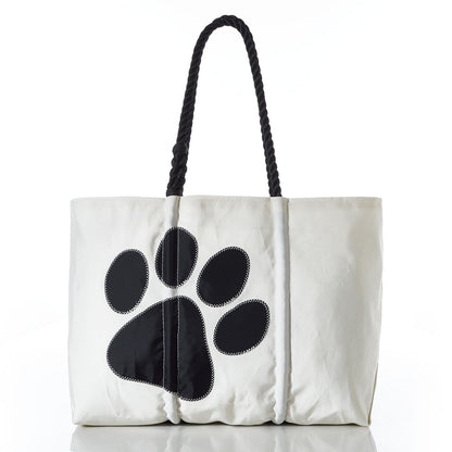 The Paw Print Large Tote with Clasp and Hanging Pocket by Sea Bags features black rope handles and a bold black paw print on white recycled sailcloth—an ideal accessory for dog lovers or as an organizer for pet supplies. by Sea Bags