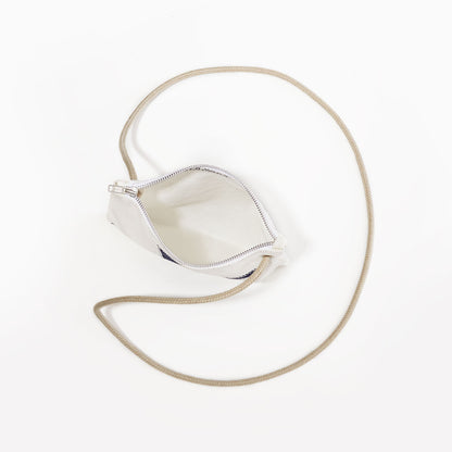 The Multicolor Nautilus Slim Crossbody Bag by Sea Bags, made from recycled sail cloth, features a small design with a white base, a long beige strap, and zippered closure—photographed from above on a plain white background. by Sea Bags