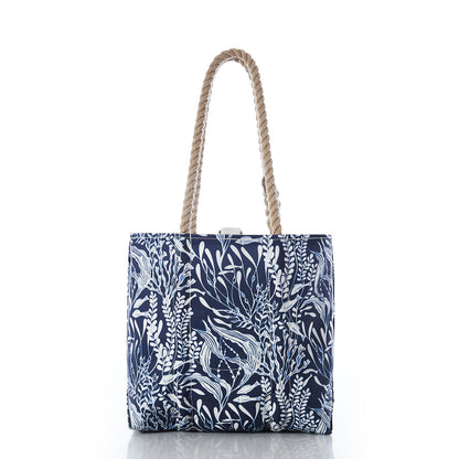 The Navy Ocean Flora Handbag by Sea Bags features a white botanical print and twisted rope handles, crafted from recycled sail cloth for an earth-friendly accessory inspired by coastal living, shown against a white background. by Sea Bags