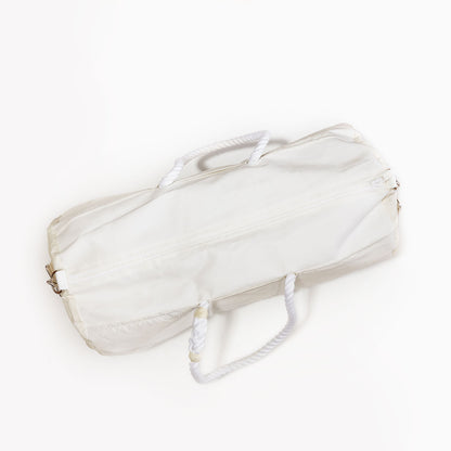 A navy vertical striped cylindrical duffel bag from Sea Bags, crafted from recycled sail cloth and featuring a durable marine grade zipper closure with two white rope handles, photographed on a plain white background. by Sea Bags