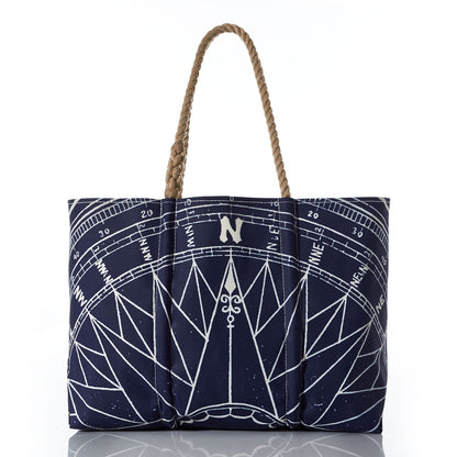 Introducing the Navy True North Large Tote by Sea Bags—a spacious navy blue tote crafted from recycled sailcloth, featuring a striking white nautical compass rose design and brown braided handles. Displayed against a white background, its the perfect nautical gift. by Sea Bags