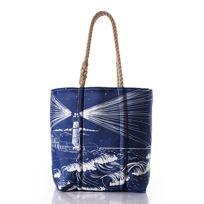 The Lighthouse Beacon Medium Tote by Sea Bags features Portland Head Light shining over waves on recycled sail cloth with nautical rope handles.