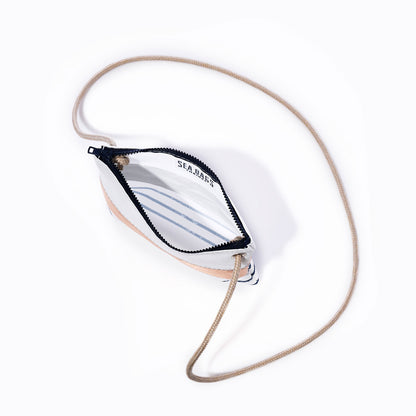 A Rose Gold-on-Navy Mariner Stripe Slim Crossbody Bag by Sea Bags, featuring a small handcrafted design with a tan rope strap and zippered closure, is shown open to reveal a white interior with blue Breton stripes and the SEA BAGS logo printed inside, photographed on a plain white background. by Sea Bags