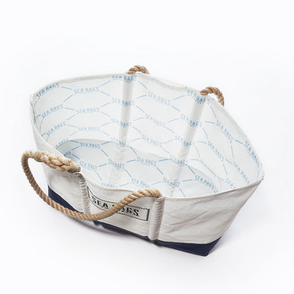 The Sailmakers Tote with Clasp and Hanging Pocket by Sea Bags is a white tote bag with rope handles, crafted from recycled sail cloth. Featuring a dark navy base, the open bag reveals Sea Bags printed on the inner lining. by Sea Bags