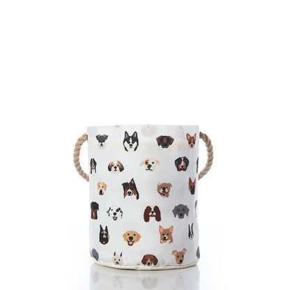 The Sea Bags Popular Pups Print Bucket Bag is a cylindrical white pet organizer featuring rope handles and decorated with a playful pattern of various dog breed faces, shown centered on a white background. by Sea Bags
